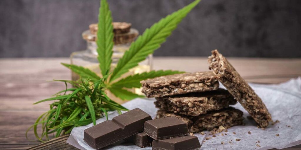 cannabis edibles, chocolate and cookies on a table with a weed leaf