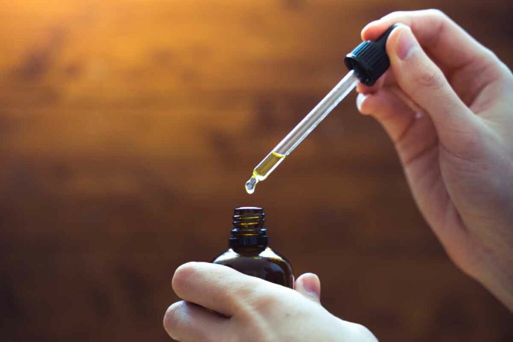 Hands holding a CBD oil dropper