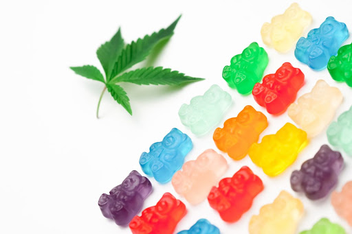 A Cannabis leaf next to a variety of colourful gummy bears.