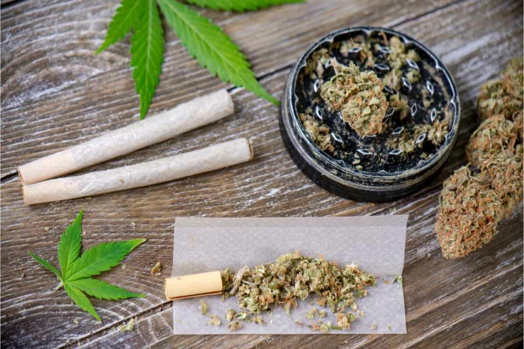 Cannabis joints with rolling paper, flower, and grinder