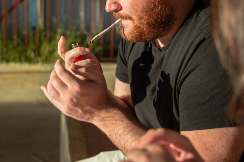 A man smoking weed by lighting a joint.